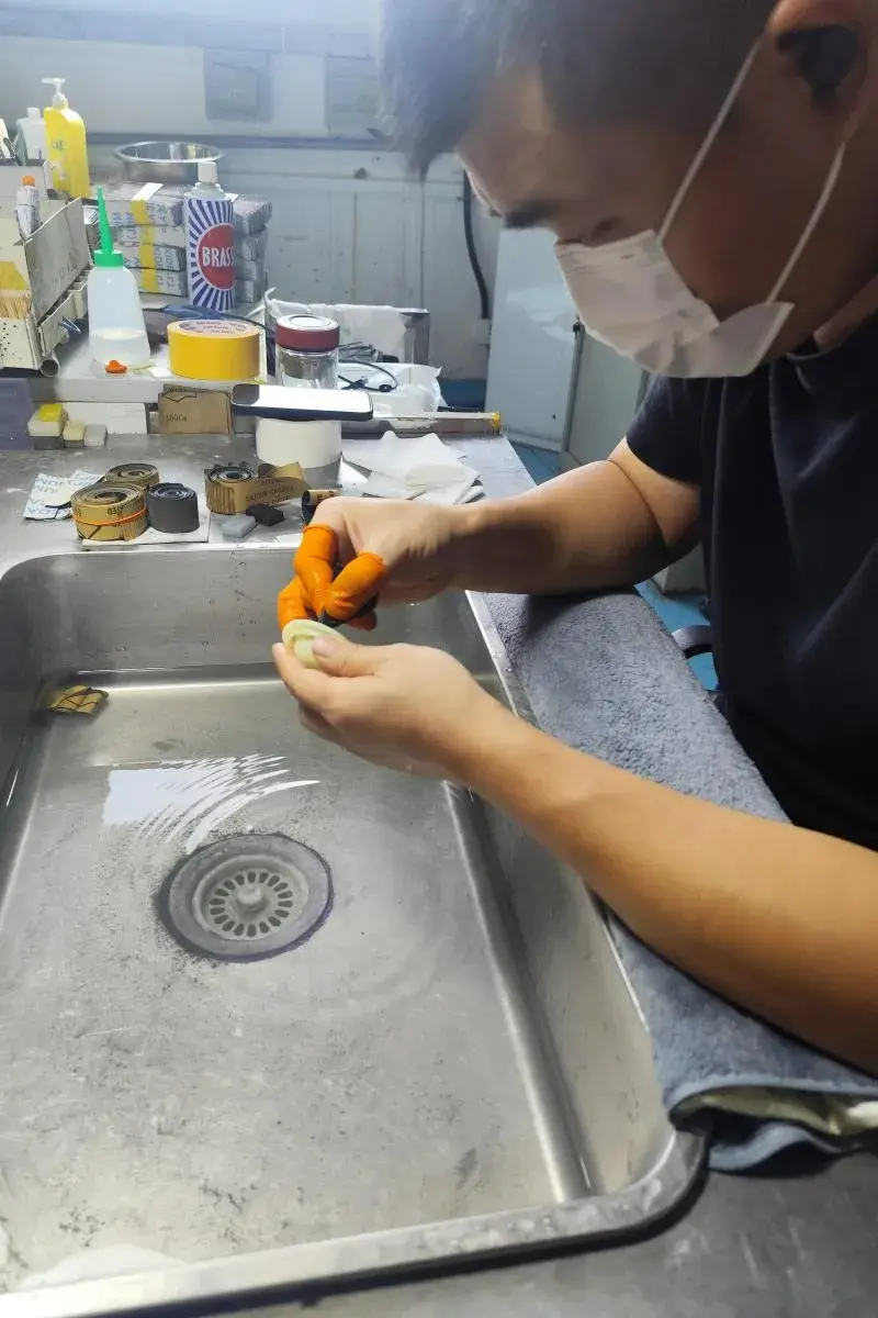 A skilled technician performing manual sanding on a plastic component to achieve a perfectly smooth surface finish before painting.