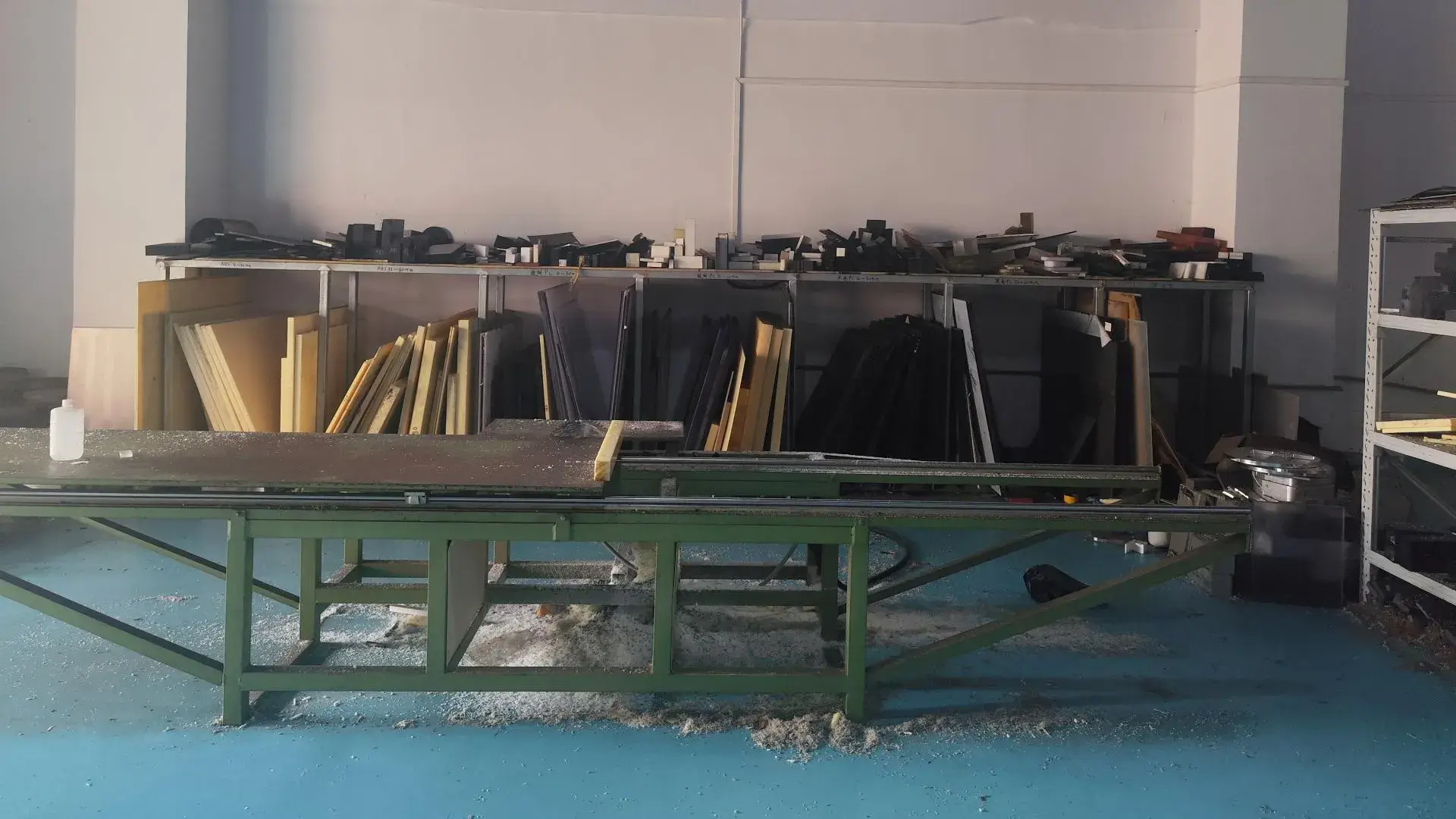 Raw material storage and preparation area featuring a variety of engineering plastics and metals with industrial cutting equipment.